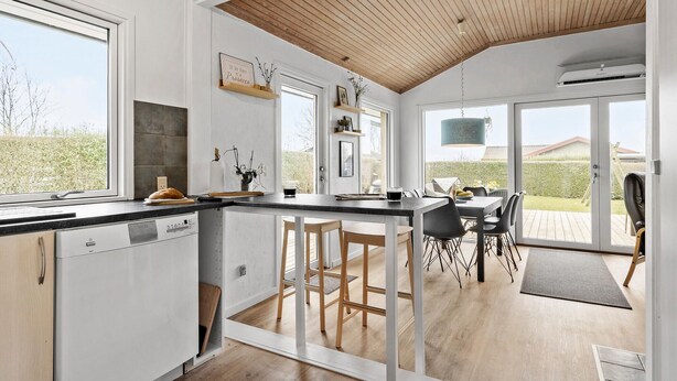 A modern kitchen with a wooden ceiling, a dining area with a table and chairs, and a view of the outdoors. - 2 bedroom awesome home in Bogense (Bogense)