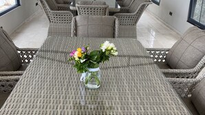 En matgrupp i rotting med en vas med blommor på bordet, omgiven av bekväma stolar.
