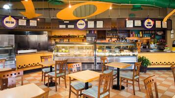 A restaurant with a checkered floor, wooden tables and chairs, a counter with a display case, and hanging signs.