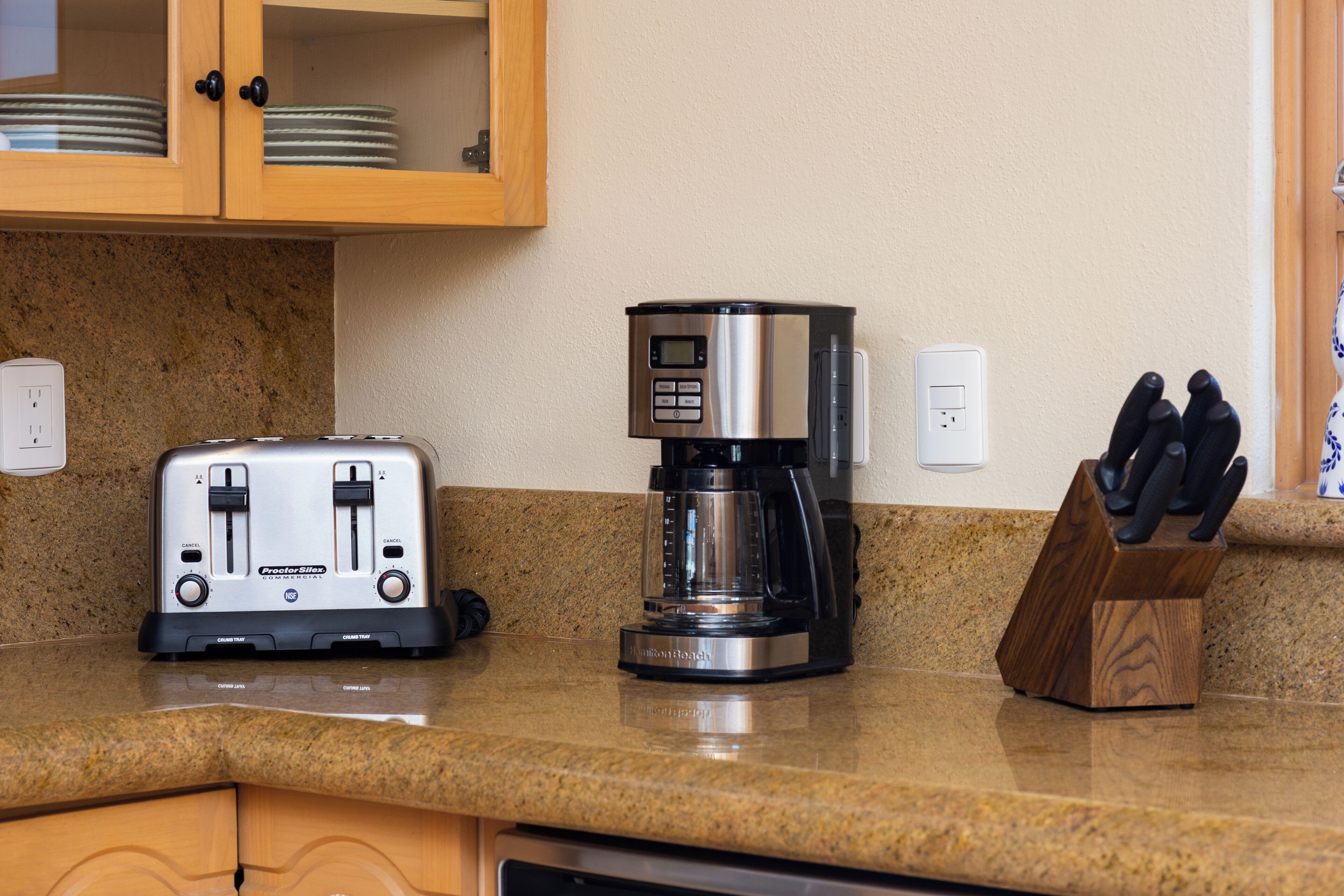 A kitchen with a toaster, a coffee maker, and a knife block on the counter.