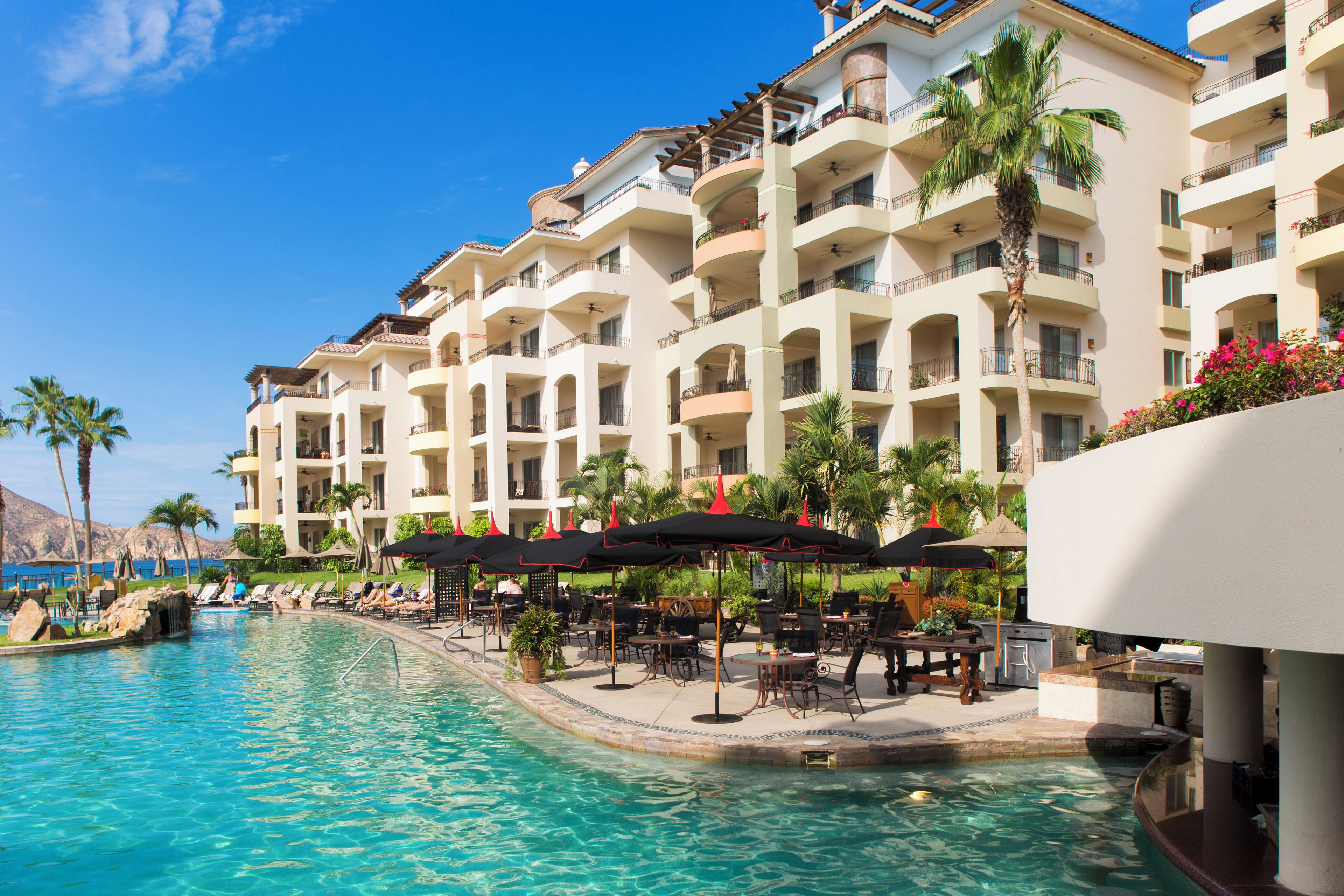 Un hotel con piscina, mobiliario exterior y balcones.