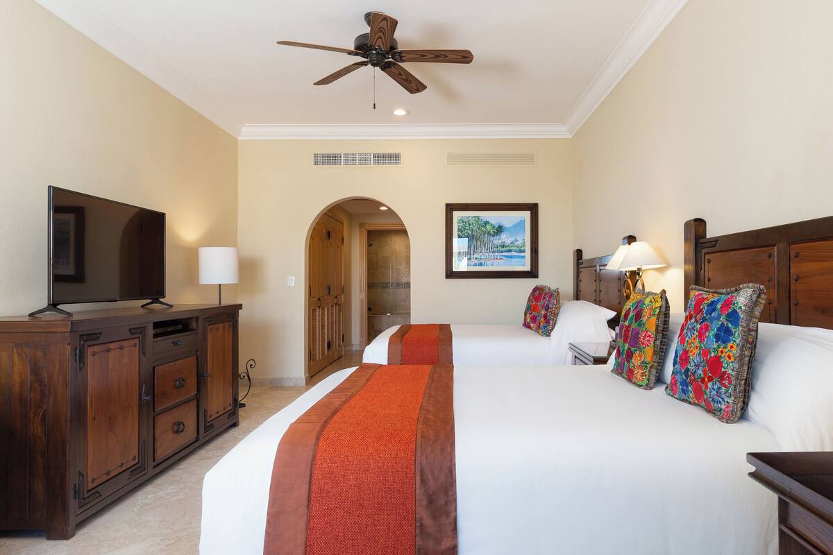 Ein Hotelzimmer mit einem großen Bett, einem Fernseher, einem Schreibtisch und einem Deckenventilator.