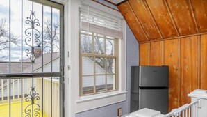 Ein Zimmer mit einem großen Fenster, einem schwarzen Kühlschrank und einer Holzzieldecke.