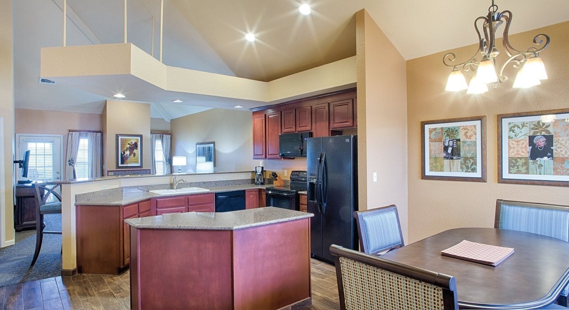 A spacious kitchen with granite countertops, a central island, and a dining area with a table and chairs.