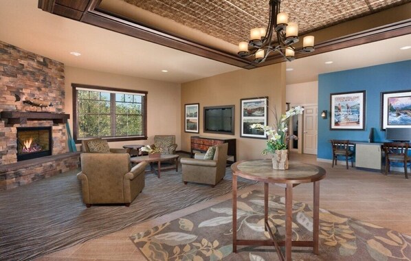 A spacious living area with a fireplace, comfortable seating, a television, and framed artwork on the walls.