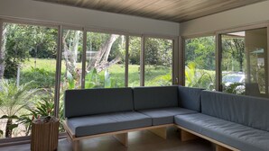 A modern interior with a sectional sofa, large windows, and a ceiling light fixture.