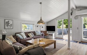 A living room with a sofa, coffee table, and TV. There is a window and a door leading to an outdoor area. - 3 bedroom nice home in Fjerritslev (Fjerritslev)