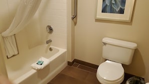 Een badkamer met een bad, toilet en een ingelijst beeld aan de muur.
