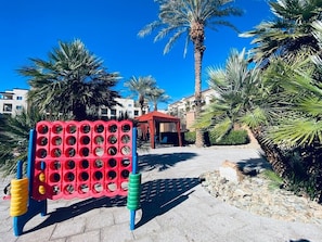 Eine rote und blaue Spielkonstruktion mit mehreren Löchern, umgeben von Palmen und blauem Himmel.