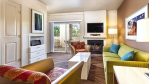 Una habitación de hotel con chimenea, televisor y balcón con mobiliario exterior.