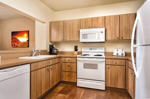 A modern kitchen with wooden cabinets, a white stove, a microwave, a sink, and a dishwasher. - Las Vegas | VIP Vegas Retreat | Pool + Hot Tub | 3BR Sleeps 6 (Las Vegas)
