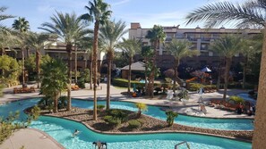 Ein Resort-Poolbereich mit mehreren Schwimmbecken, Palmen und Liegestühlen.