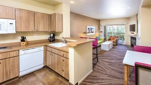 A modern kitchen with a dishwasher, a coffee maker, and a microwave. There is a dining area with a sofa and a TV. - Las Vegas | Romantic Vegas Retreat | Pool + Hot Tub (Las Vegas)