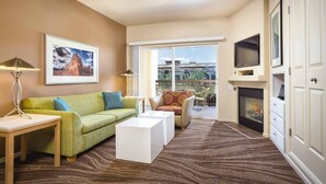 A living room with a green sofa, a white coffee table, a fireplace, and a large window. - Las Vegas | Romantic Vegas Retreat | Pool + Hot Tub (Las Vegas)