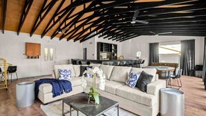 Un ampio soggiorno con soffitto alto, un divano, un tavolino da caffè e un'area da pranzo con tavolo e sedie.