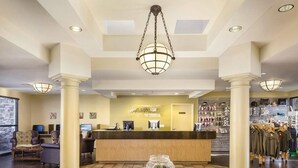 Un hall d’hôtel comprenant un comptoir d’accueil, un espace salon et un présentoir de vêtements.