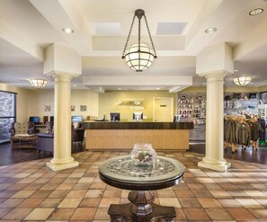 Un hall d’hôtel comprenant un comptoir d’accueil, un espace salon et un présentoir de vêtements.