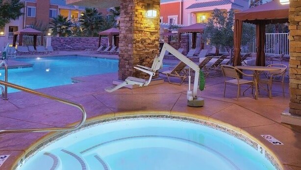 Une piscine avec un jacuzzi circulaire, des chaises longues et un pilier en pierre.