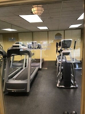 Un gimnasio con cintas de correr, una bicicleta estática y un espejo grande.