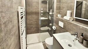 Ein modernes Badezimmer mit einer einteiligen Duschkabine, einem weißen Waschbecken und einem großen Spiegel.