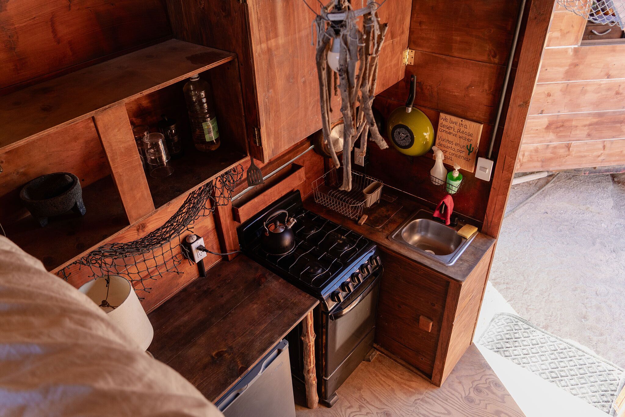 A compact kitchen with wooden cabinets, a gas stove, a sink, and a small countertop.