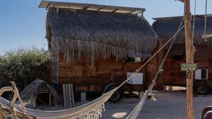 A rustic wooden building with a thatched roof, a hammock, and a sign reading "CENIZERO ASHTRAY". - Beachfront Tiny Home on the La Fortuna Surf Break - The Baja Station (San José del Cabo)