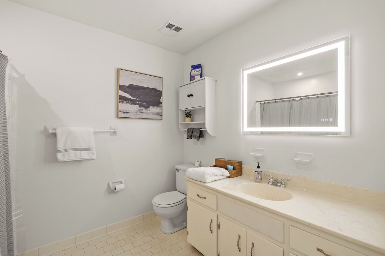 A modern bathroom with a toilet, sink, and mirror.