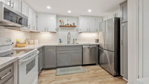 Una cocina moderna con armarios blancos, un refrigerador de acero inoxidable y un microondas.