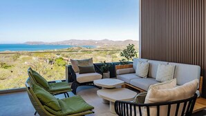 Ein moderner Außenbereich mit einer Couch, Sesseln und einem Tisch, mit Blick auf eine reizvolle Landschaft.