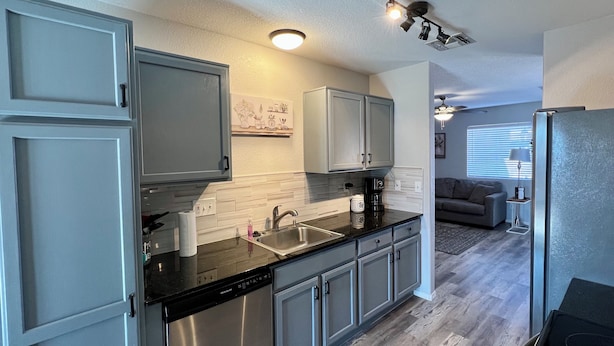 A modern kitchen with stainless steel appliances, grey cabinetry, and a built-in dishwasher. - Eastside Tucson Gem (Tucson)