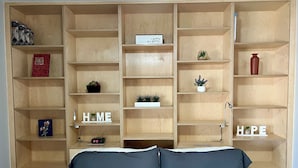 A bedroom with a bed, wooden shelving unit, and various decorative items. - Eastside Tucson Gem (Tucson)
