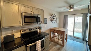 A modern kitchen with stainless steel appliances, a wooden table, and a view to the outside. - Eastside Tucson Gem (Tucson)