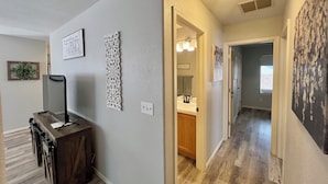 A hallway with a wooden floor, a desk with a mirror, and a wall with a 'Thank You' sign. - Eastside Tucson Gem (Tucson)