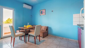 Un comedor con una mesa, sillas y un sofá. Se ve una ventana con vistas a árboles.