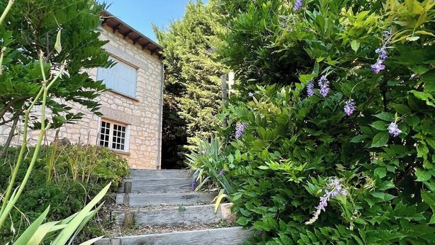 Un bâtiment en pierre avec un escalier en bois menant à une porte.