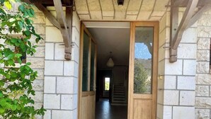 Une entrée en pierre, avec une porte en bois et un paillasson.