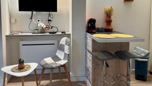 A compact kitchenette with a flat-screen TV, a coffee machine, and a small potted plant. - Casa Cloutiers #1 -Studio RDC -Hyper Centre Brive (Brive-la-Gaillarde)