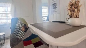 Una cocina moderna con encimera blanca, un televisor negro montado en la pared y una decoración vegetal en un lateral.