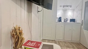 Una habitación con televisión montada, control remoto, un libro y un jarrón decorativo.