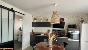 Eine moderne Küche mit Essbereich, ausgestattet mit einem runden Tisch, Stühlen, einer Pendelleuchte und integrierten Geräten.