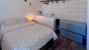 Ein Schlafzimmer mit einem Bett, einem Schminktisch, einem Wandregal und einem Schreibtisch.