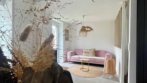 Ein modernes Wohnzimmer mit einem rosa Sofa, einem runden Couchtisch und einem großen Fenster.