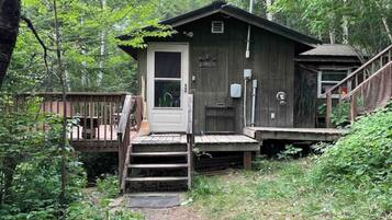 A rustic cabin with a wooden deck, a front door, and a small porch.