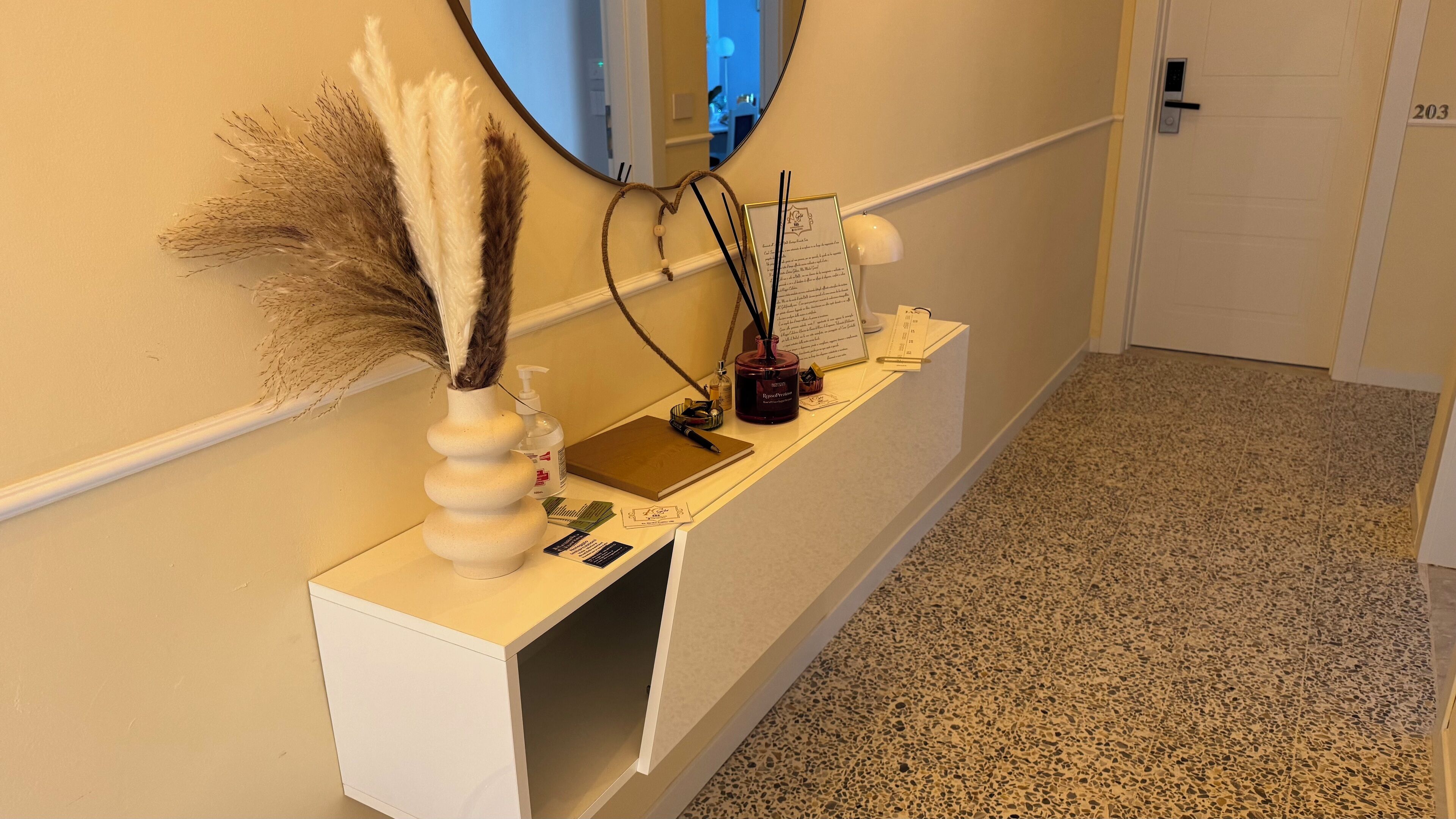 A reception desk with a white vase, a mirror, a notepad, and a pen.