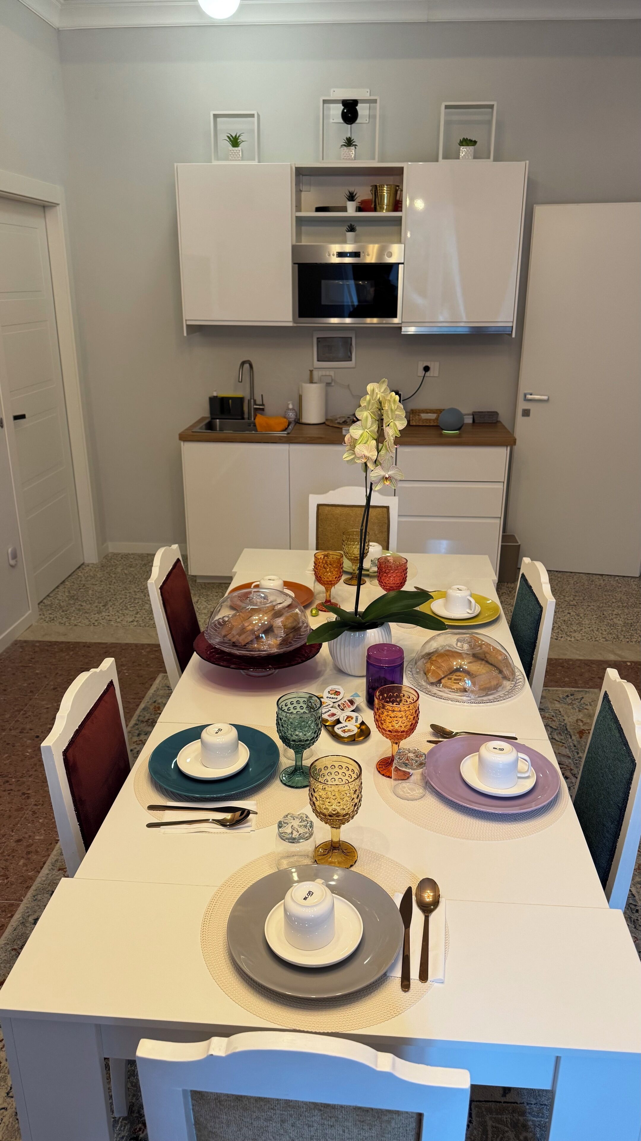 Ein Esstisch mit Tellern, Gläsern und Besteck, umgeben von Stühlen.