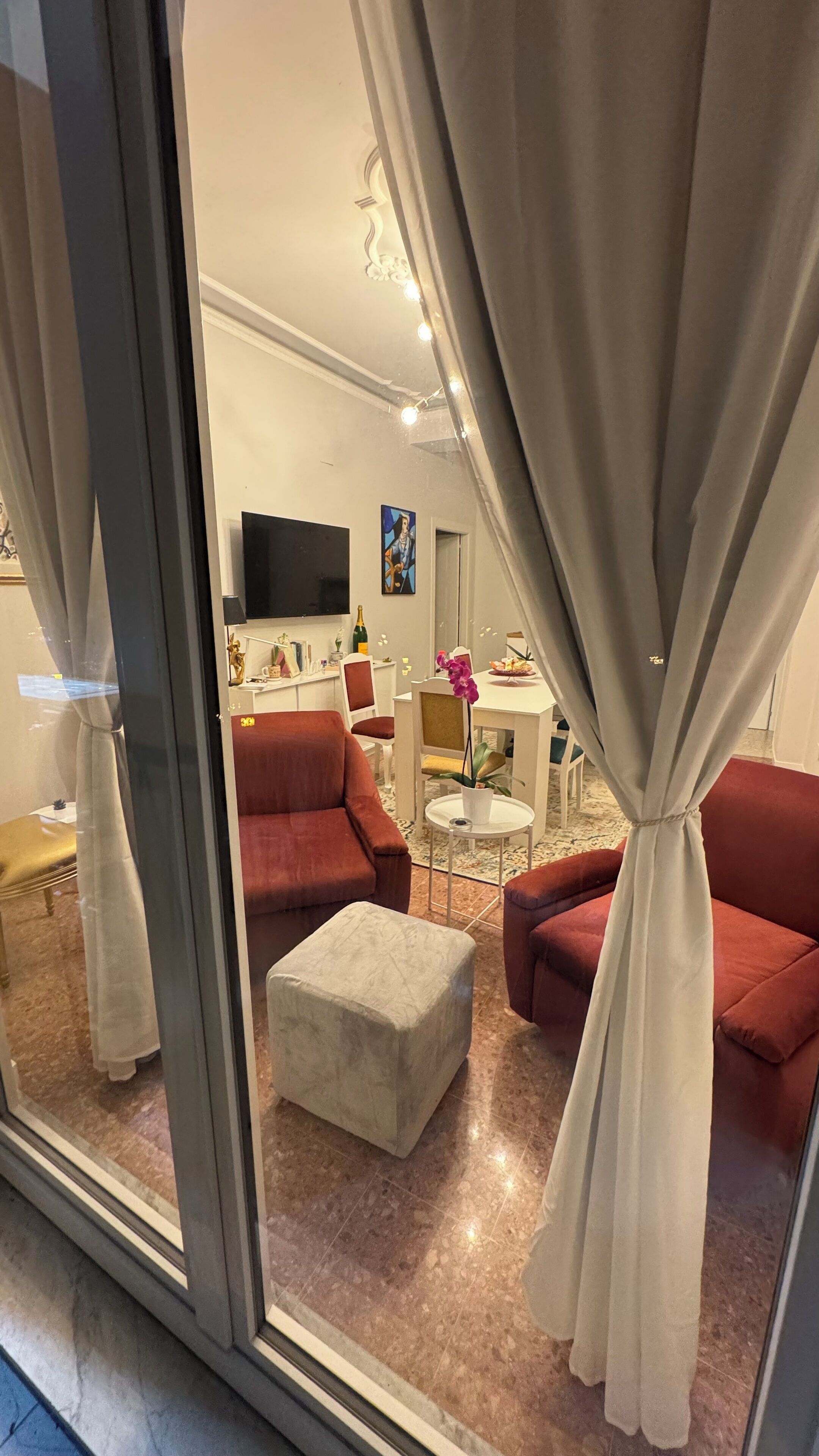 Una sala de estar moderna con sofás rojos, un reposapiés blanco y una zona de comedor con una mesa y sillas blancas.