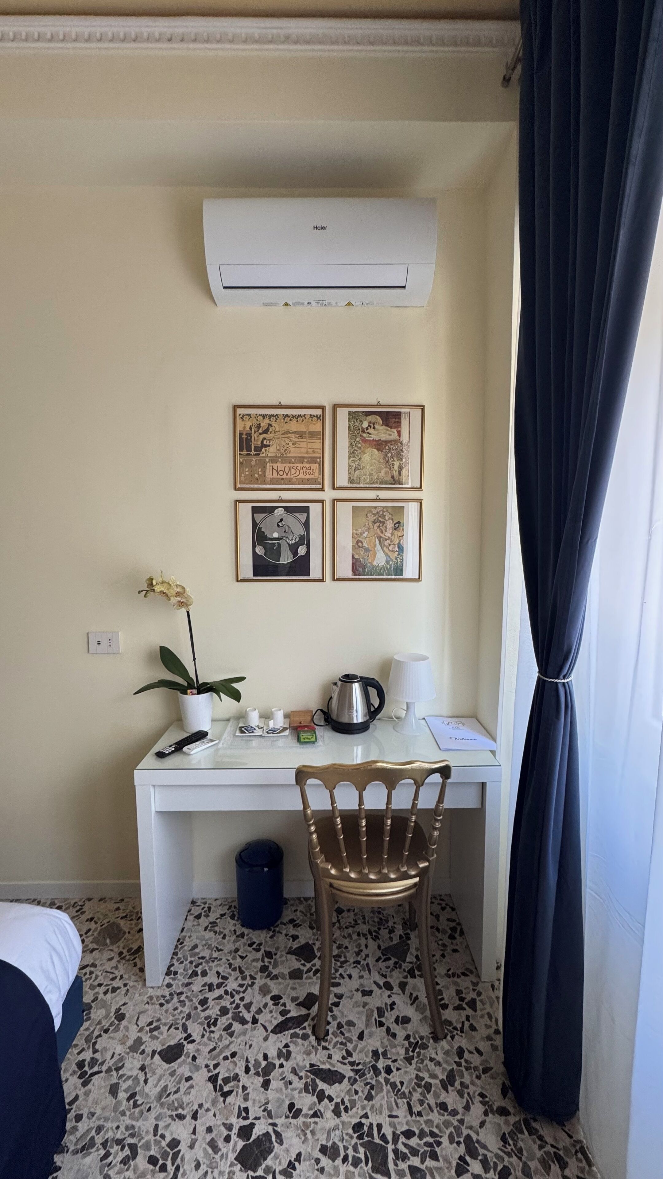 Um espaço de trabalho pequeno e bem organizado, com mesa, cadeira e ar condicionado fixado na parede.