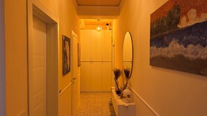 Un couloir avec une porte, un miroir et un tableau accroché au mur.