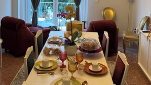 Comedor con candelabro, mesa lista para una comida y vistas al exterior a través de amplios ventanales.