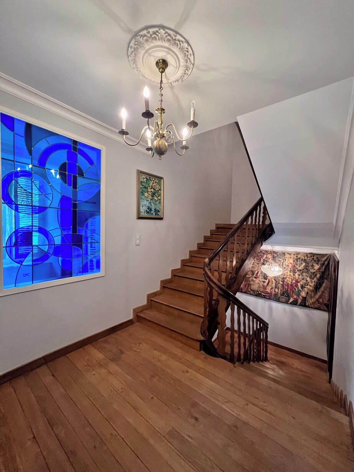 A staircase with wooden steps and a black railing, leading to a landing with a patterned carpet.